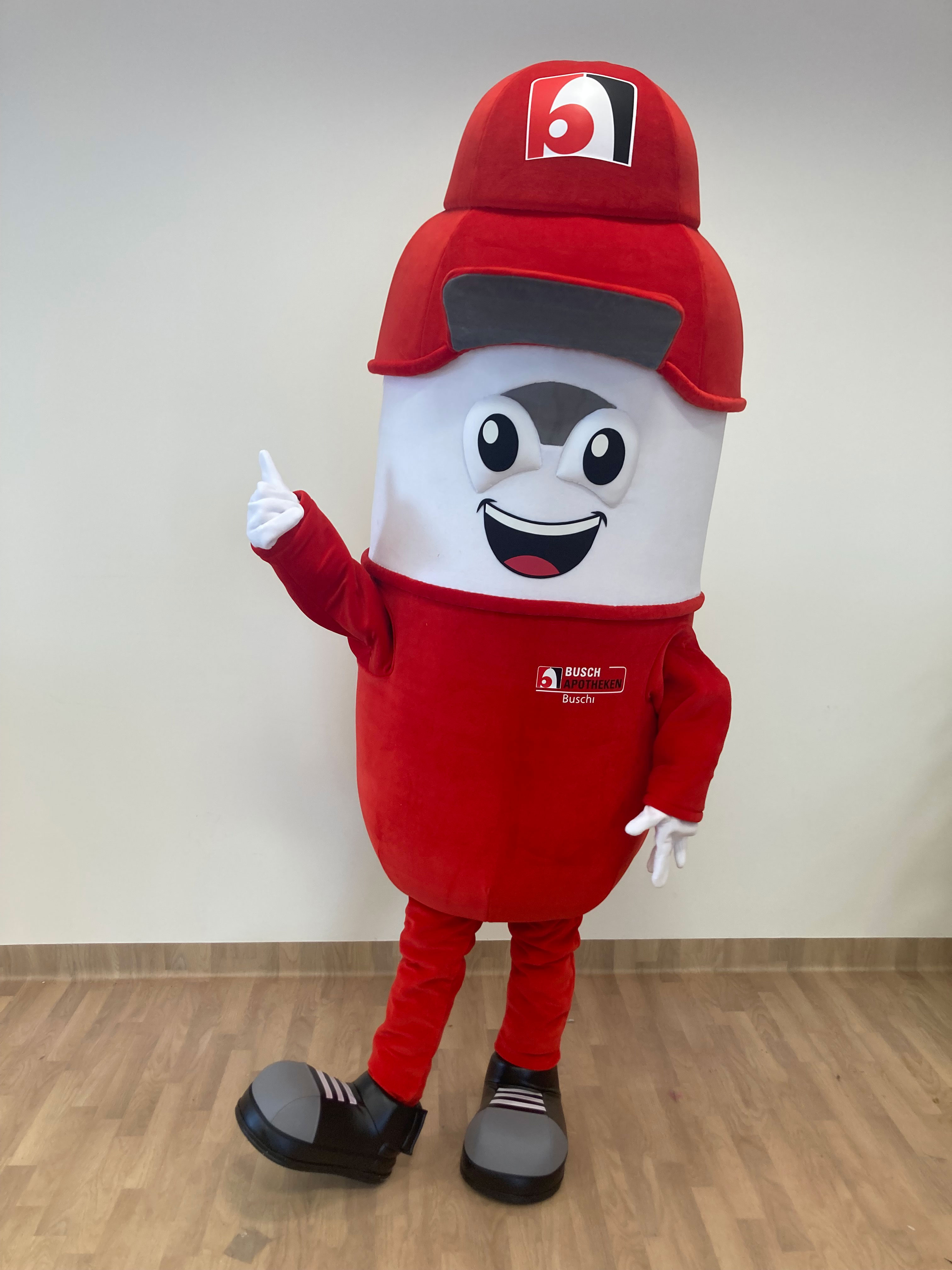 Na fotografii widnieje kostium reklamowy w postaci kapsułki na leki pozujący do zdjęcia w siedzibie firmy Elabika